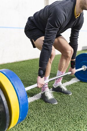 Man training with barbell on sports ground