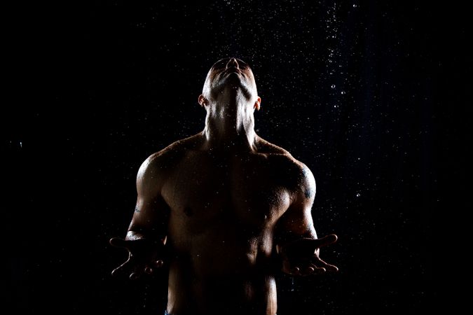 Muscular male under rain