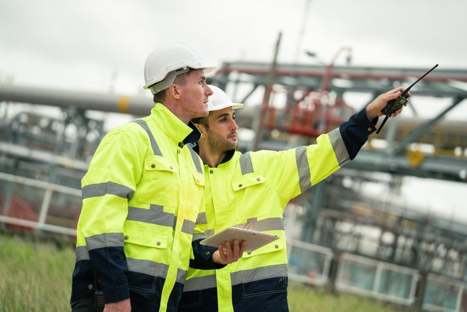 Engineer worker watching work monitor on digital tablet and talking to colleague
