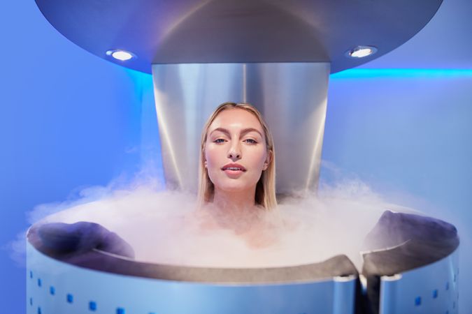 Blonde woman standing in cryotherapy chamber