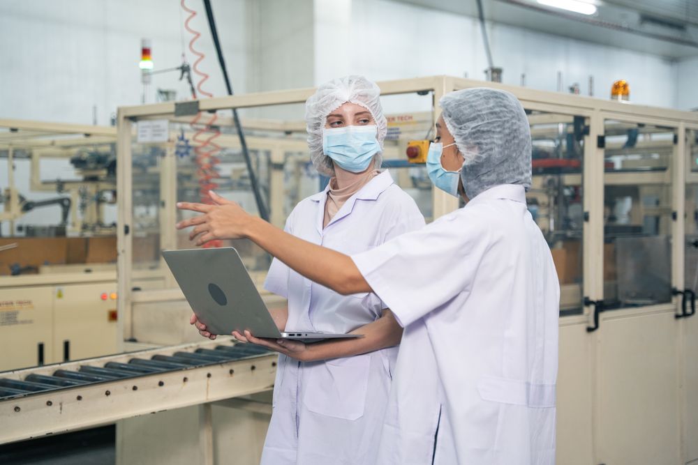 Industrial workers inspecting quality control of canned fish factory