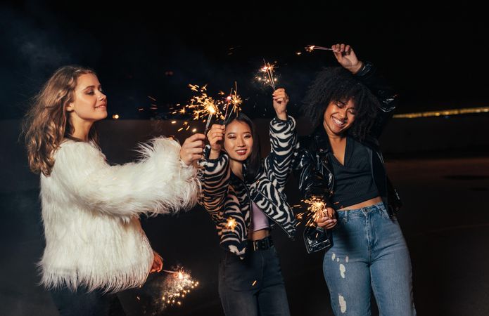 Three women celebrating at night with sparklers having fun