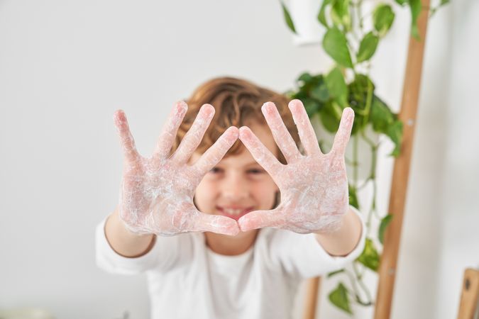 Happy boy showing soapy palms in camera