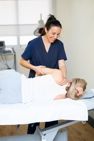 Female Physiotherapist working on her patient arm and shoulder