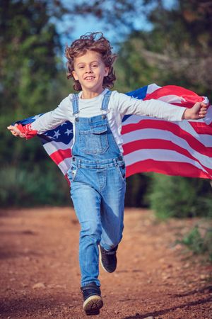 Little boy running with USA flag in nature