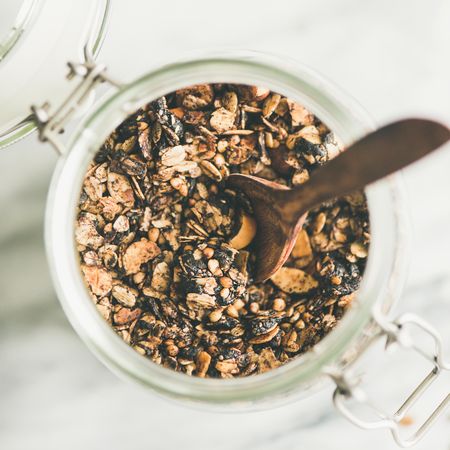 Top view glass container of homemade granola, close up, square crop