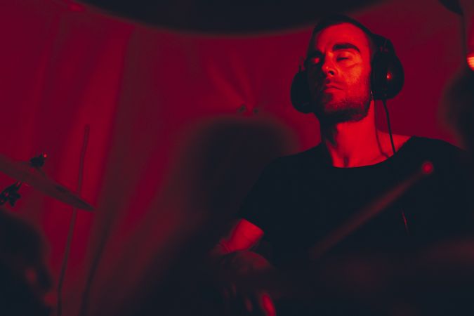 Man with drumsticks playing on drums in redness