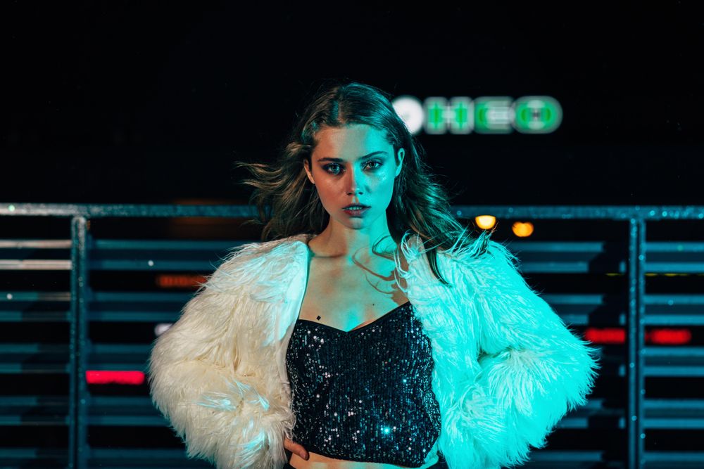 Woman in faux fur coat with hands on hip at night