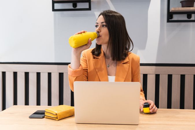 Woman drinking water during work in cafe