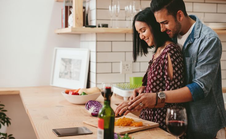 Loving young couple cutting vegetables together at kitchen counter