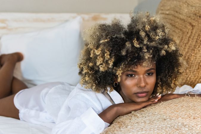 Thoughtful Black woman lying on bed in bedroom