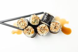 Delicious sushi rolls, soy and chopsticks on plain background, top view