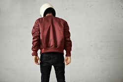 Rearshot of man looking down wearing dark red leather jacket and helmet
