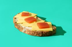 Slice of bread with cheese and marmalade isolated on a blue background