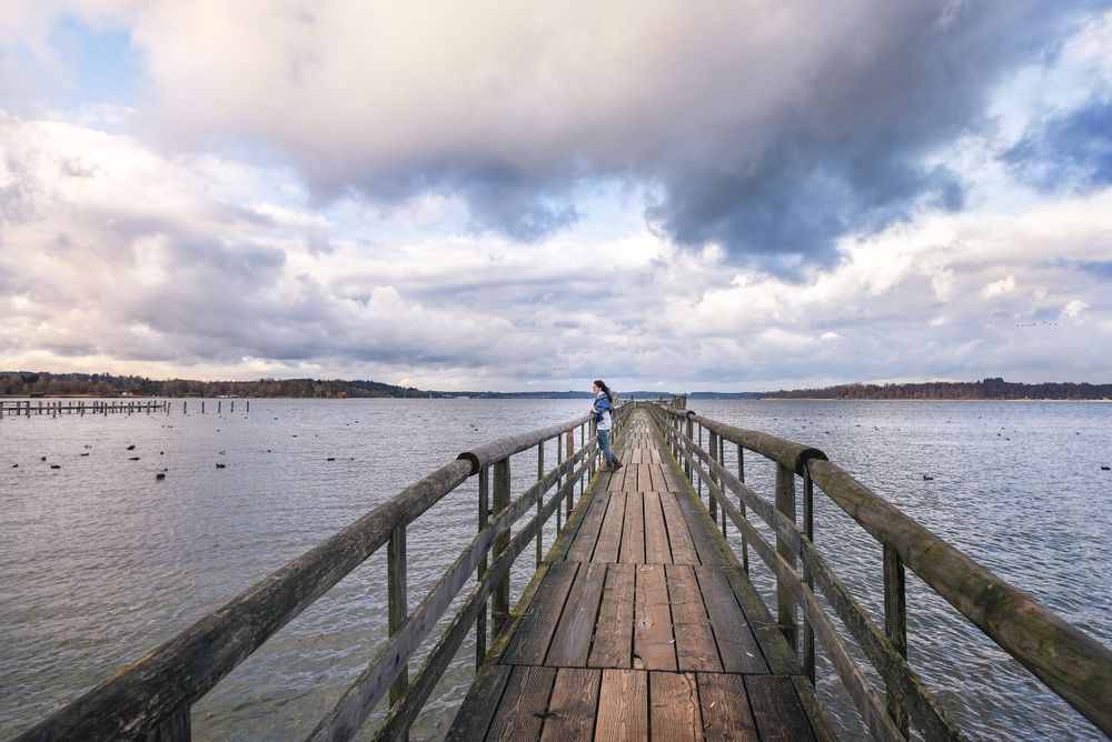 Woman standing on a bridge over Alpine lake