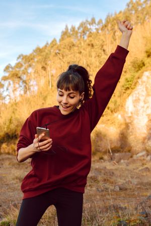Young woman with smartphone dancing