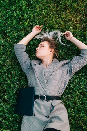Woman with tablet in stylish suit lying in grass