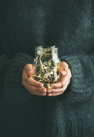 Woman holding glass jay with fairy lights inside