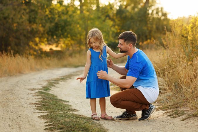 Man and daughter dressed in blue sitting along forest road