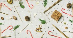 Decorations of stars, candy canes, scissors, candles on light background, wide composition