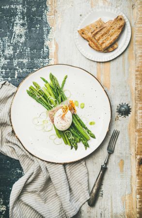 Asparagus and soft boiled egg on plate, on wooden table, with linen, and toast