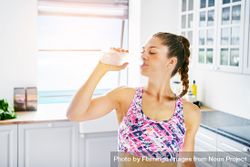 Fit woman in bright kitchen drinking from water bottle 5pLzw5