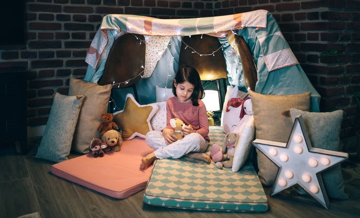 Girl playing with stuffed animals in a teepee