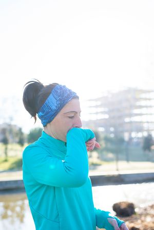 Woman in ear warmers working out outdoors on sunny fall day