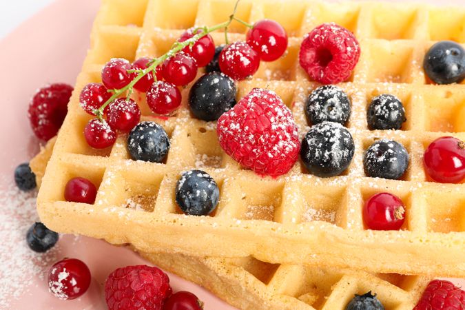 Belgian waffles with berries on plate as background, closeup