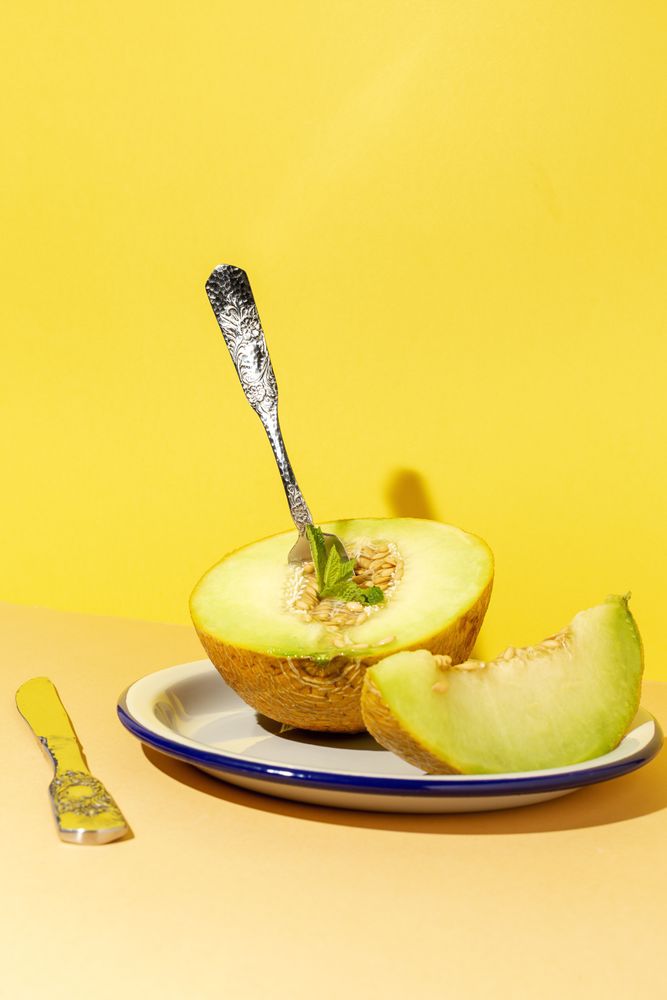 Sliced small melon on plate with spoon and fork