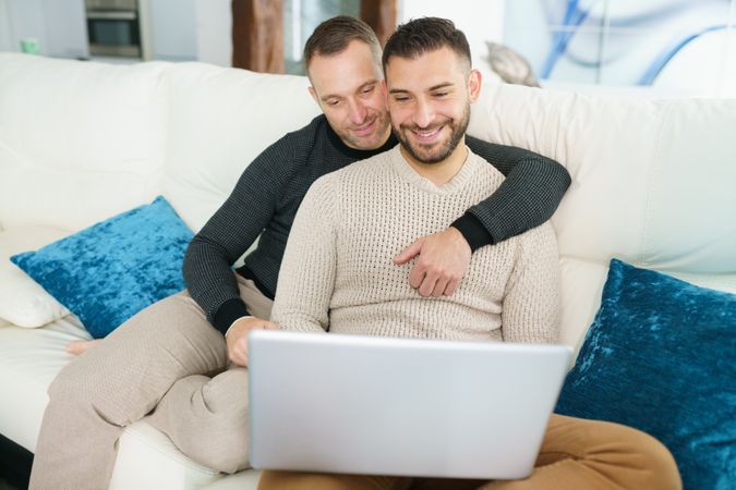 Male couple chilling on couch with laptop