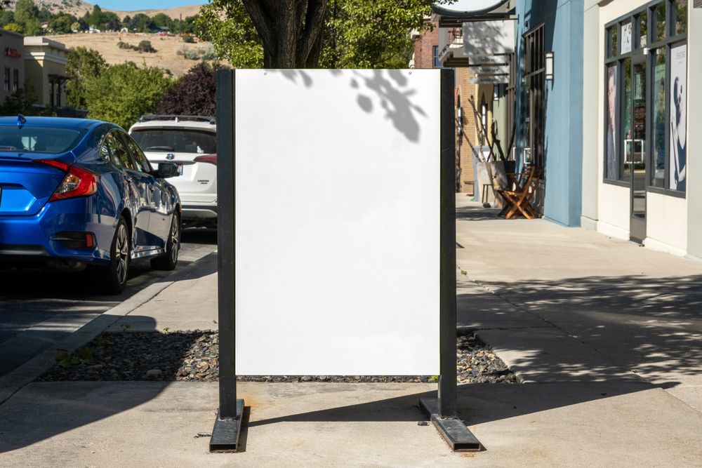Metal sign poster mockup on street outside shops