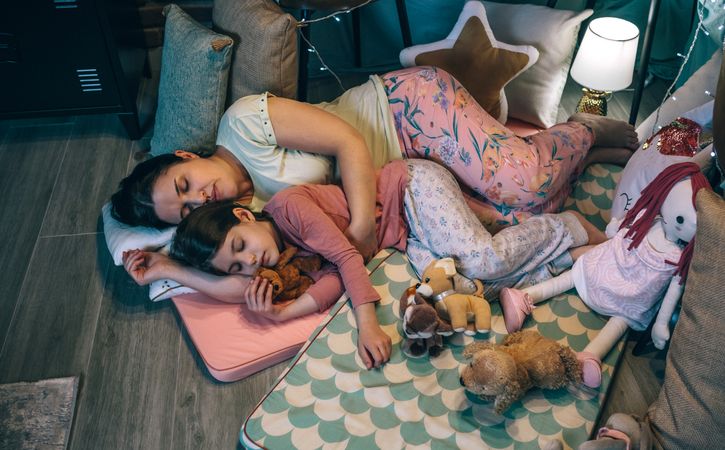 Mother embracing to little daughter asleep at night. Security and family protection concept.