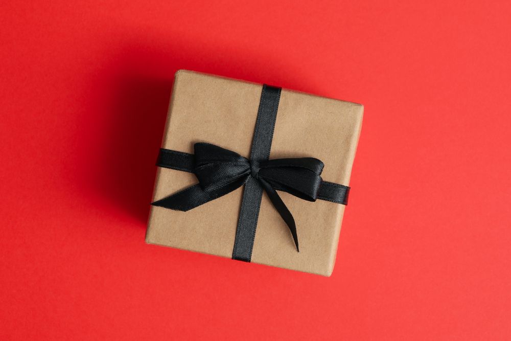 Gift box with dark bow on red background