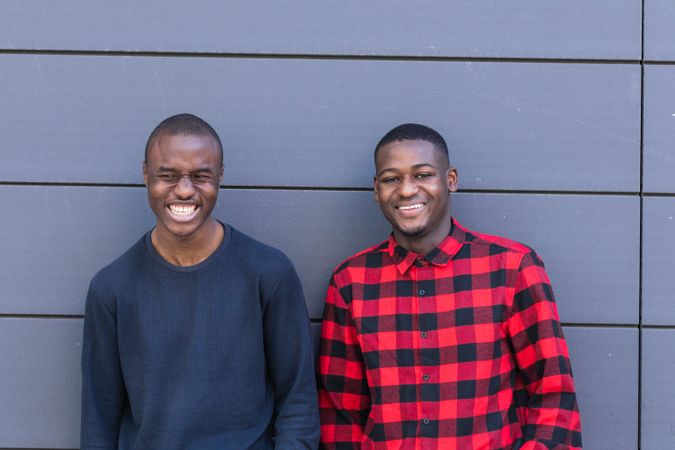 Happy Black male friends against gray wall