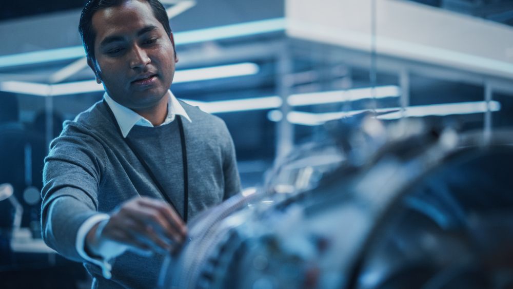 Multiethnic Chief Engineer Explaining the Technology Behind a Modern Turbofan Aircraft Engine to Team of Colleagues
