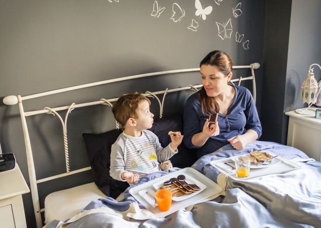 Mother and son having breakfast in bed