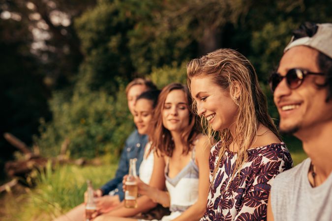 Portrait of happy young woman sitting with her friends by a lake