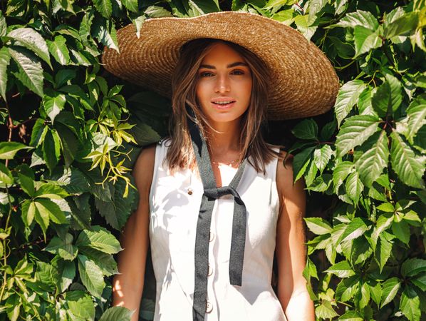 Woman emerging from bush in straw hat