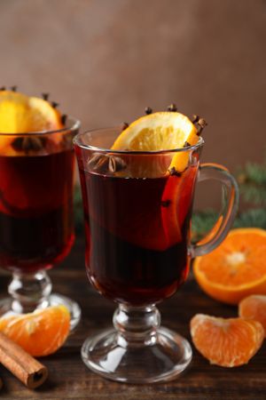 Glasses of tasty mulled wine with orange on wooden background, space for text