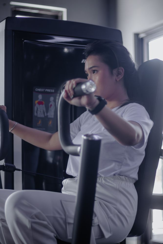Focused woman enhances chest power utilizing pressing machine in