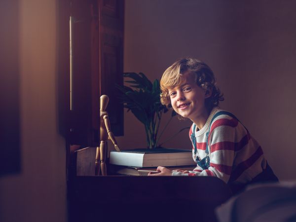 Charming kid smiling at table against book