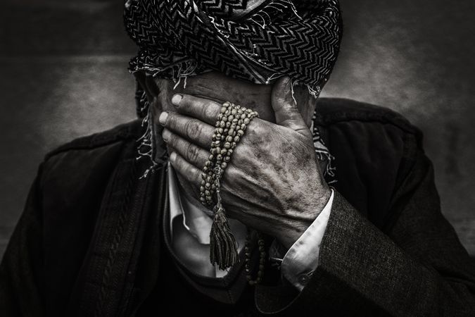 Cropped image of older man crying and holding prayer bead