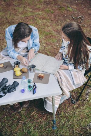 Young women reviewing road map in campsite