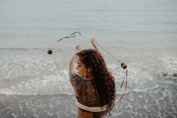 Tattooed woman dancing with balls near sea