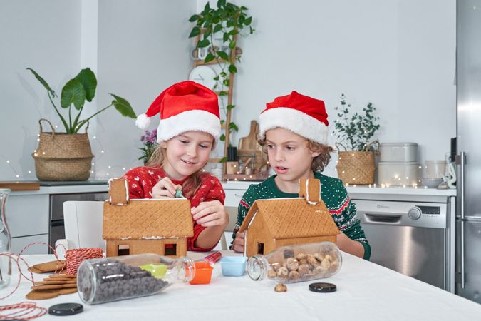 Children applying icing on gingerbread houses