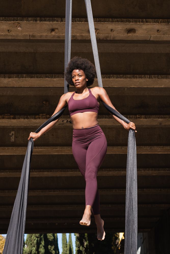 Slim woman doing yoga with aerial silks in city