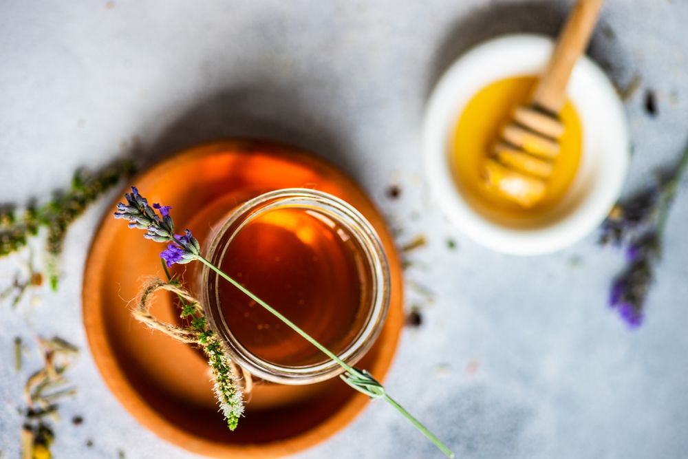 Top view of floral honey with glass of honey and floral flowers