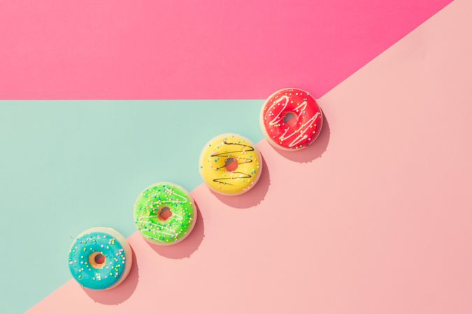 Row of colorful donuts on pastel geometric background