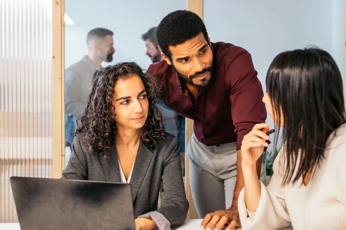 Coworkers in a company meeting analyzing company data. They are in a meeting room of a modern coworking office space